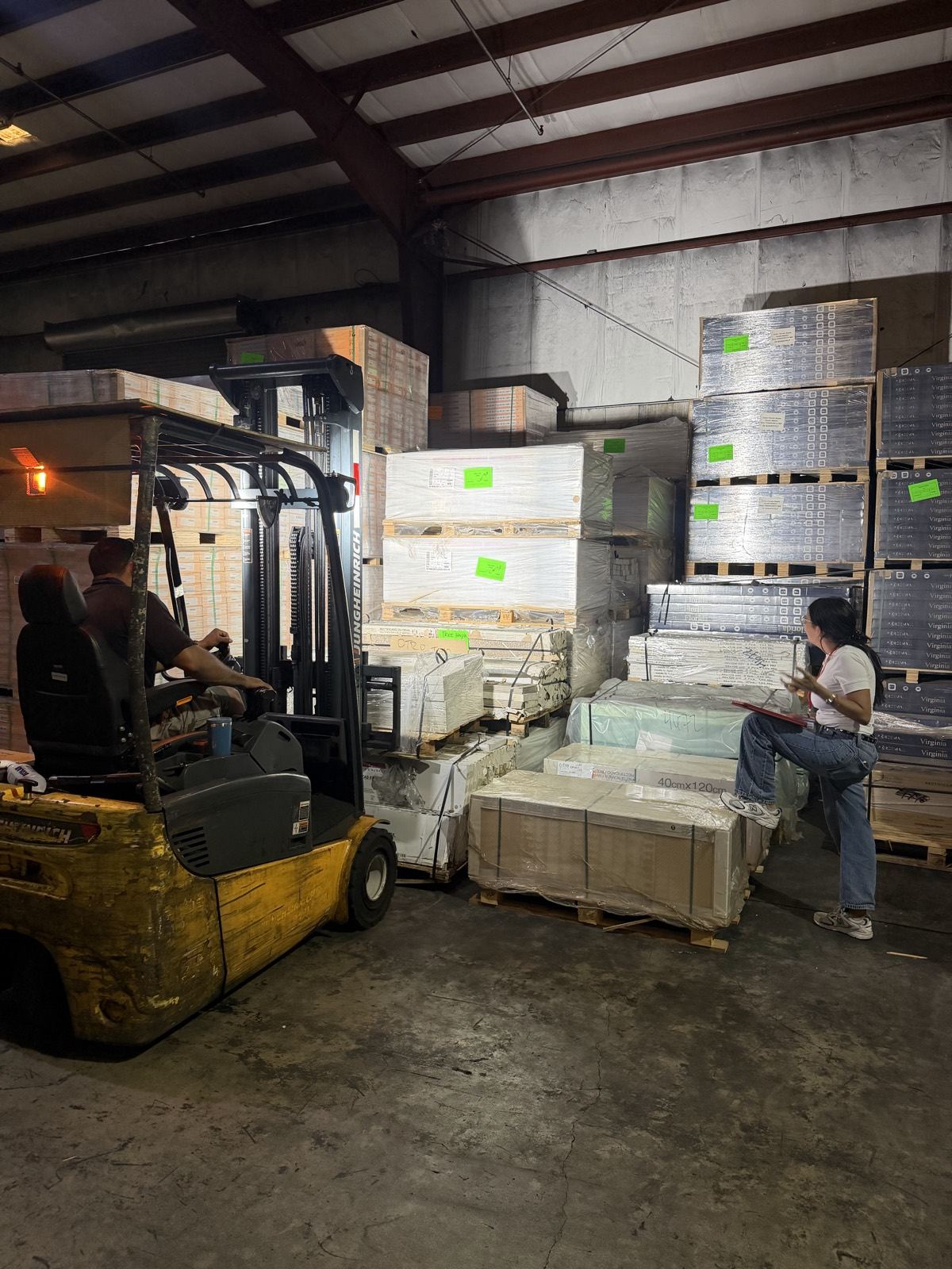 Pallets de cerámica en el racking del almacén, con un montacargas y revisión de inventario